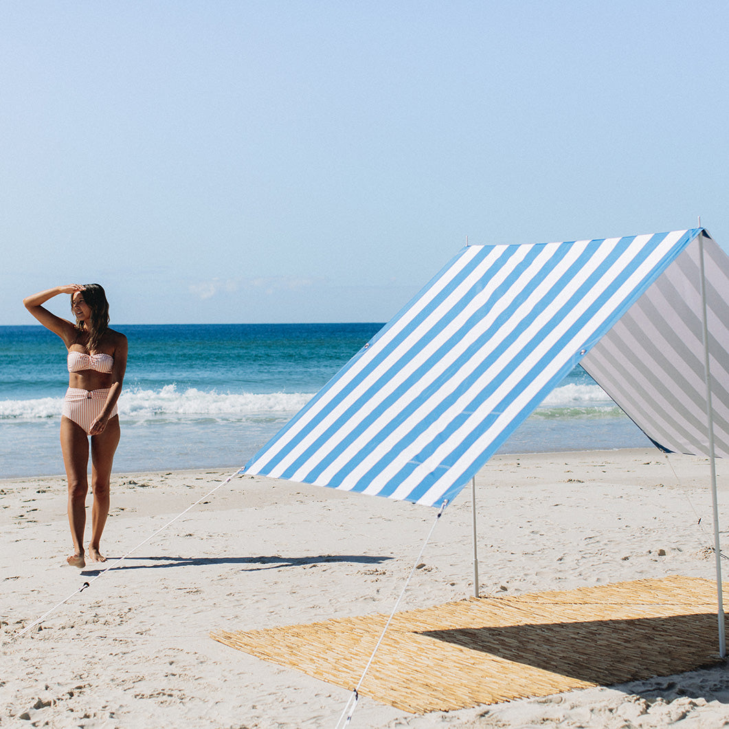 Woman walking back to Beach Tent in Blue and White Stripe after being for a swim at the Beach