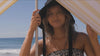 Girl standing under Yellow and White Nautical Striped Beach Tent on the beach with black hat and bikini staring at camera holding beach shelter pole at Byron Bay Beach