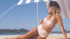 beach shelter nautical blue on byron bay beach with girl lying under beach tent in white and pink striped bikini looking out to the ocean lighthouse from byron bay in background